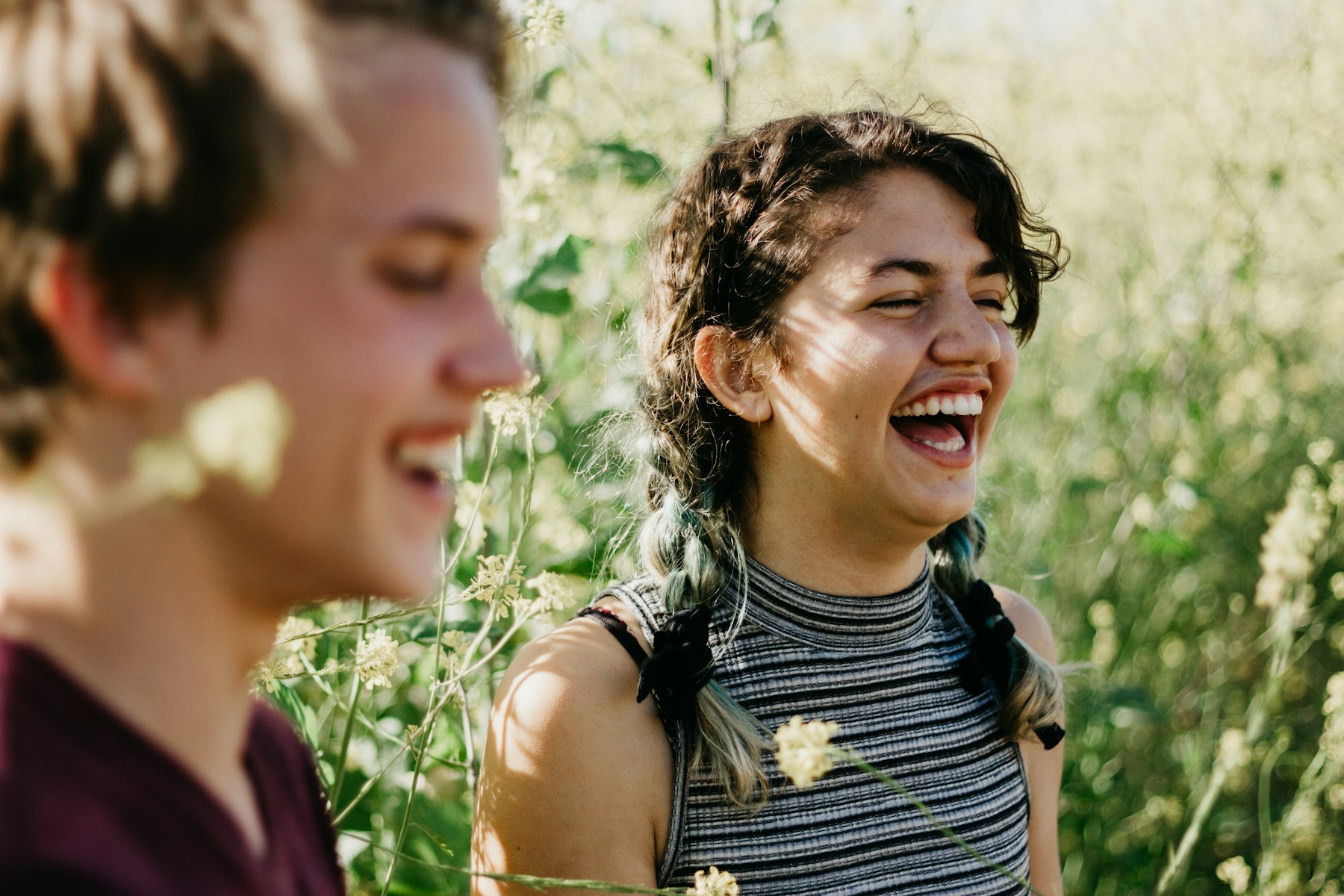 Junge Menschen lachen im Grünen Zwei junge Menschen lachen gemeinsam zwischen hohen Gräsern.