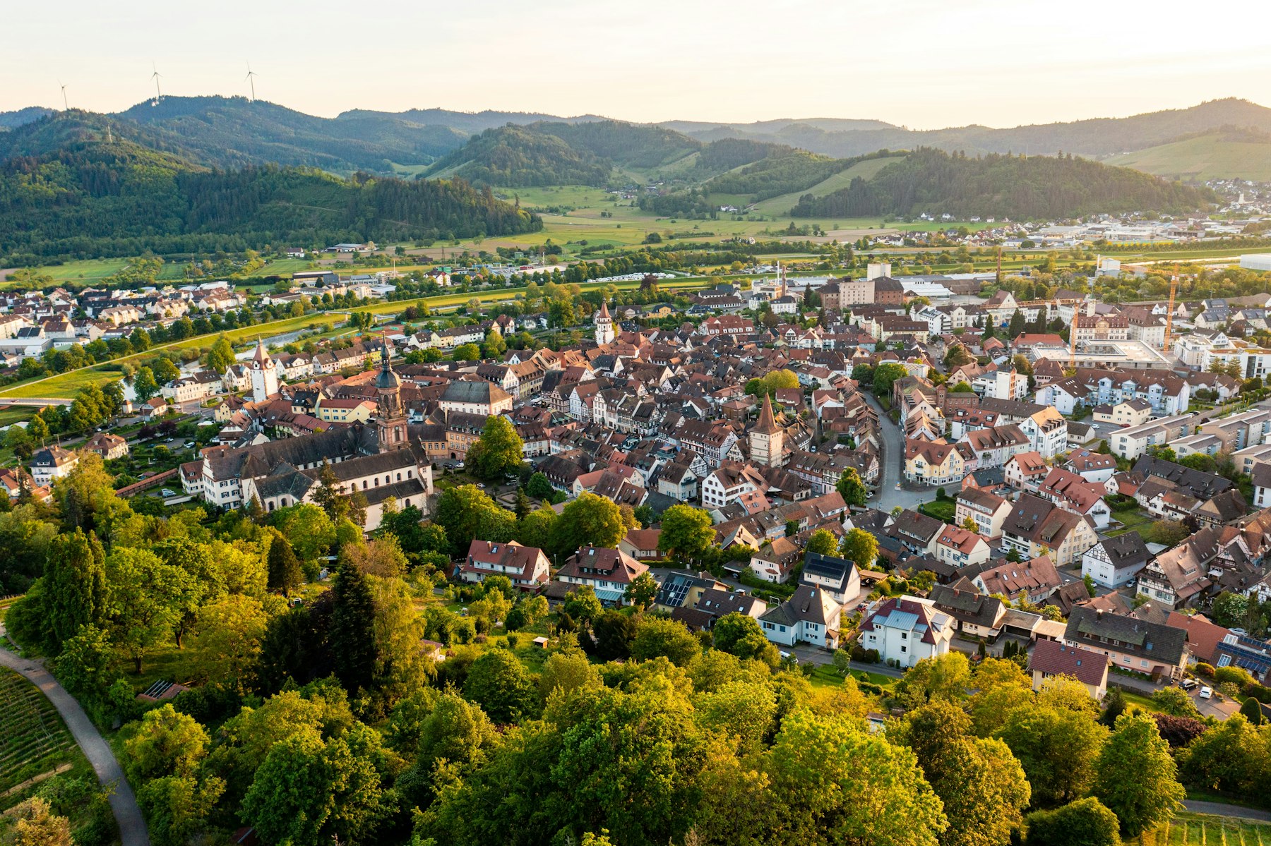 Kleinstadt im Abendlicht Blick über eine Kleinstadt zwischen bewaldeten Hügeln im Abendlicht.
