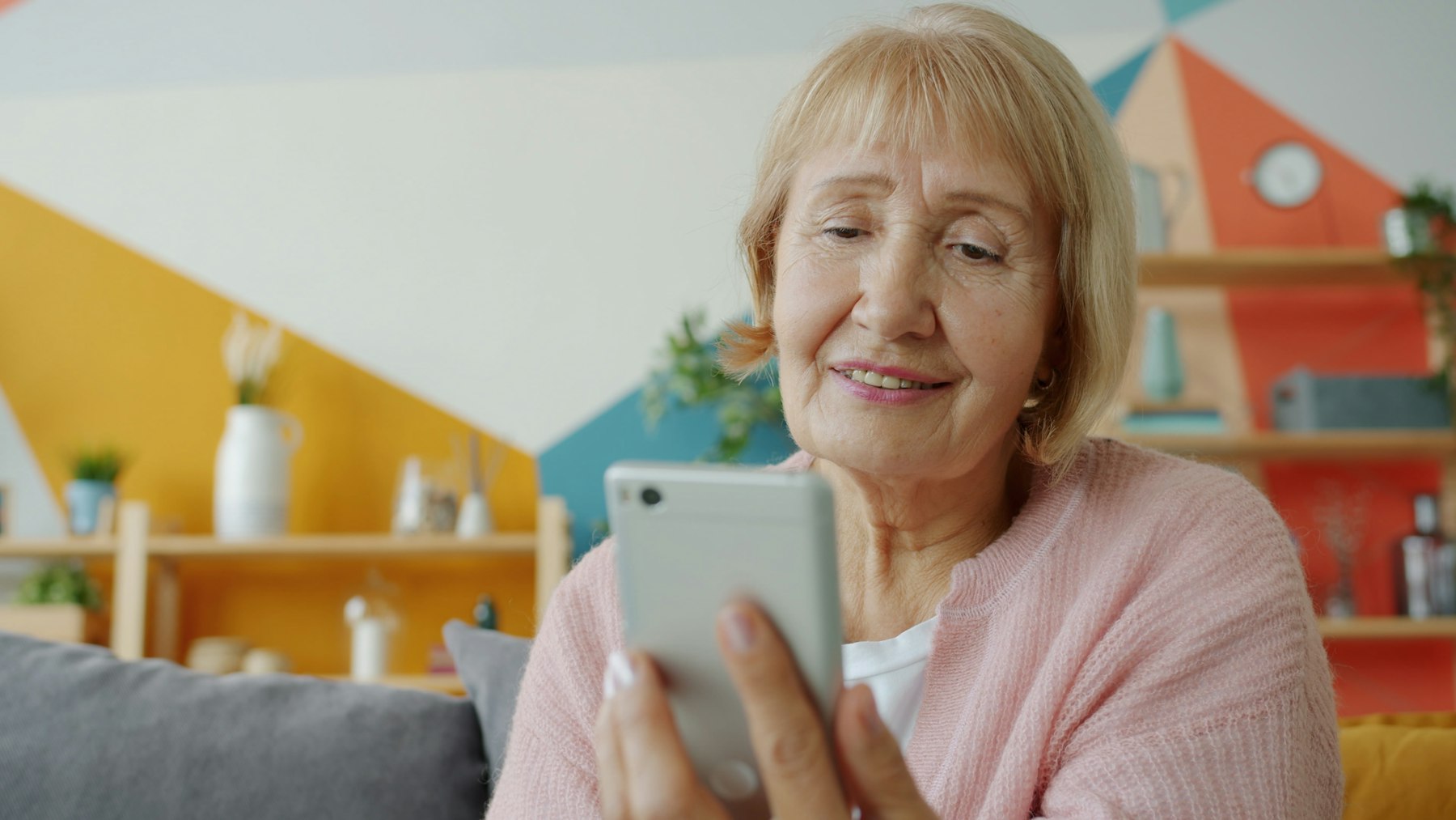 Freude am Smartphone Eine Frau mit blonden Haaren lächelt beim Blick auf ihr Smartphone.